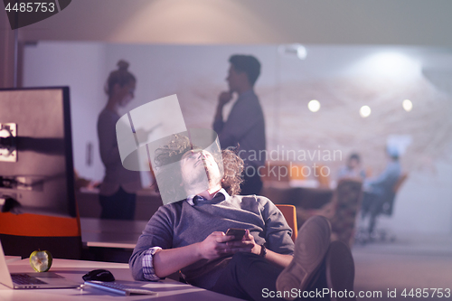 Image of businessman sitting with legs on desk at office