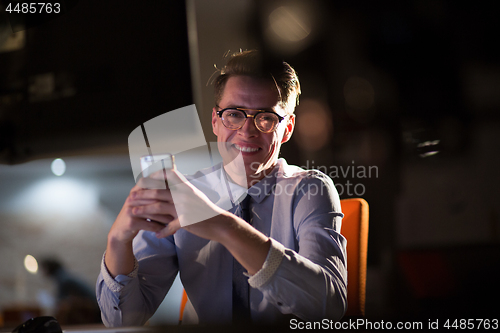 Image of man using mobile phone in dark office