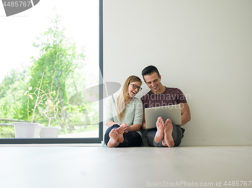 Image of couple using laptop on the floor at home