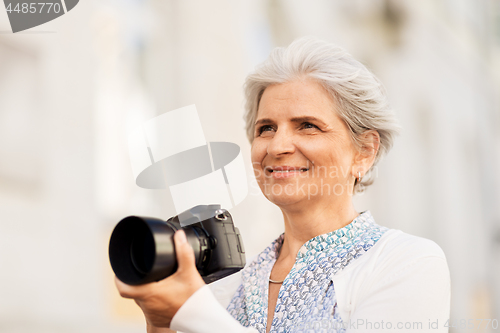 Image of senior woman photographing by digital camera