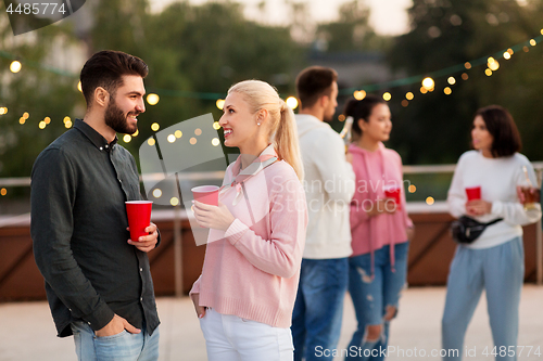 Image of friends with drinks in party cups at rooftop