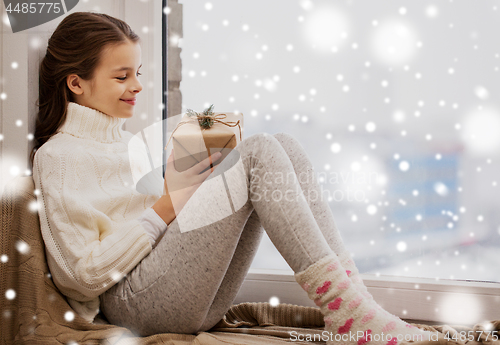 Image of girl with christmas gift sitting on sill at home