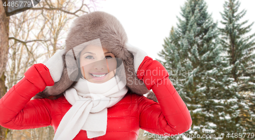 Image of happy woman in fur hat over winter forest