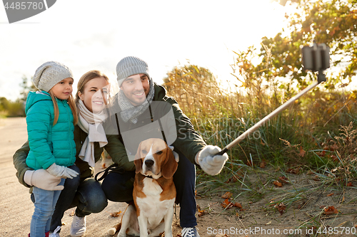 Image of happy family with dog taking selfie in autumn