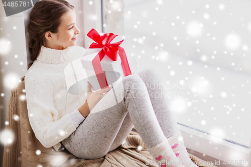 Image of girl with christmas gift sitting on sill at window