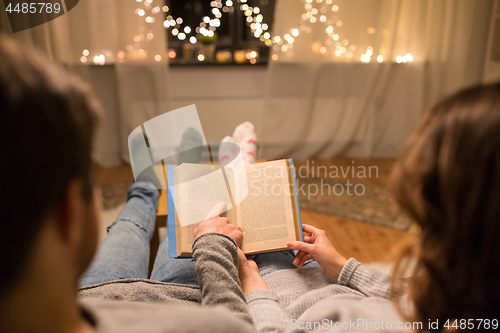 Image of close up of couple reading book at home