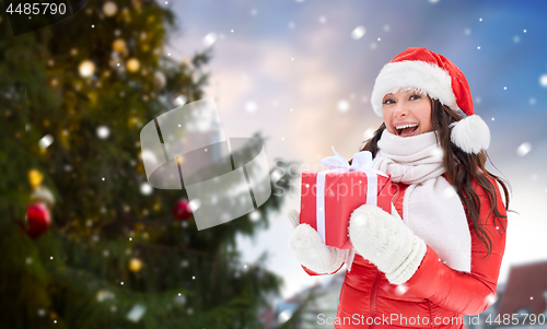 Image of happy woman with gift over christmas tree