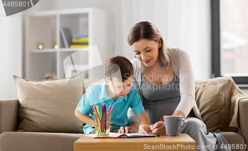 Image of pregnant mother and son with workbook at home