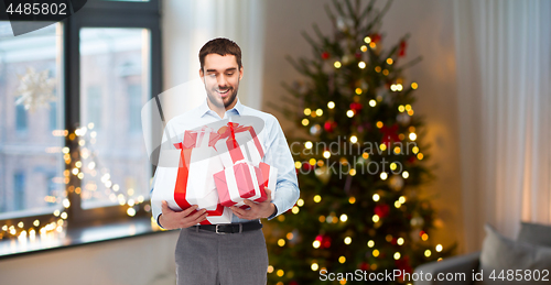 Image of happy man with christmas gifts at home