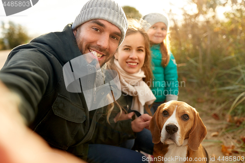 Image of happy family with dog taking selfie in autumn