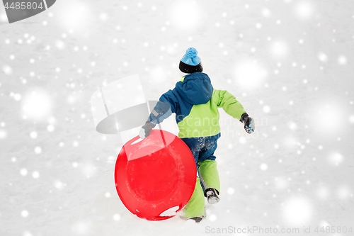 Image of happy boy with snow saucer sled in winter