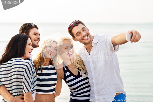 Image of happy friends taking selfie on summer beach