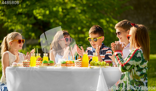 Image of happy kids with cake on birthday party in summer