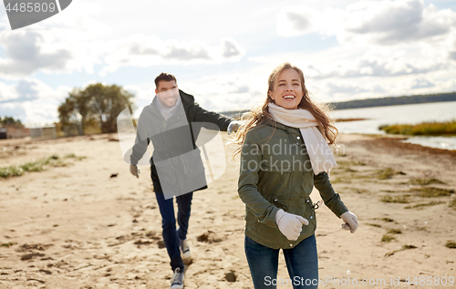 Image of couple running along autumn beach