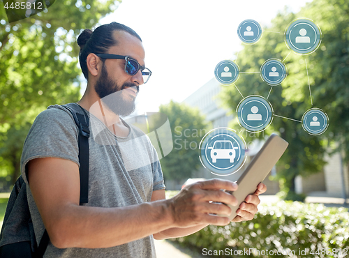 Image of man using car sharing app on tablet pc in city