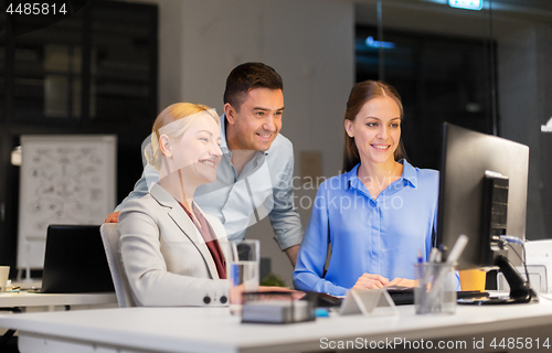 Image of business team with computer working late at office