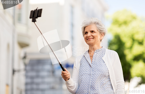 Image of happy senior woman taking selfie on city street