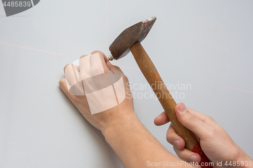 Image of Male hand hammering a nail into the wall