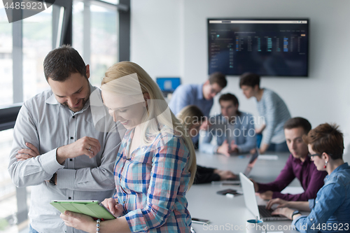 Image of Two Business People Working With Tablet in office