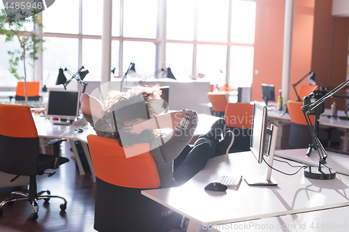 Image of businessman sitting with legs on desk