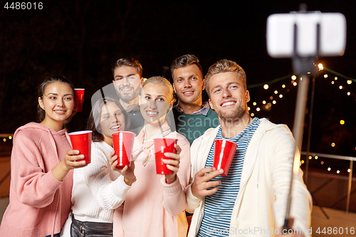 Image of friends with drinks taking selfie at rooftop party