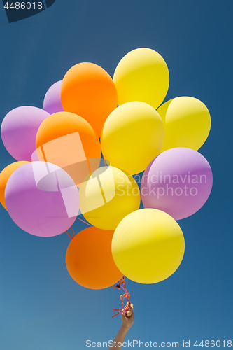 Image of close up of colorful helium balloons in blue sky