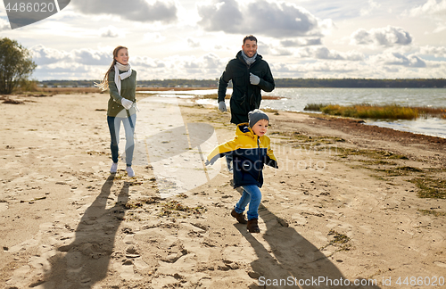 Image of happy family running along autumn beach