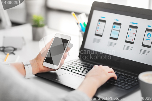 Image of web designer with smartphone and laptop at office