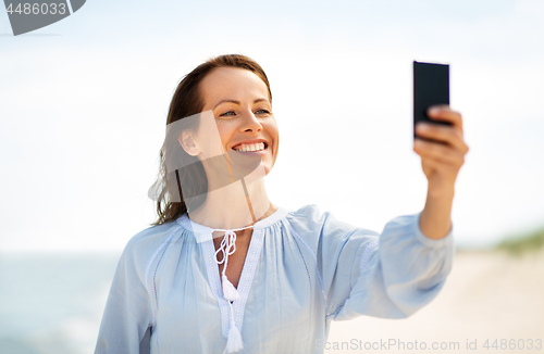 Image of happy smiling woman taking selfie on summer beach