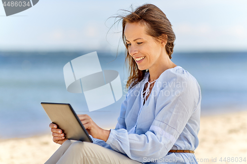 Image of happy smiling woman with tablet pc on summer beach