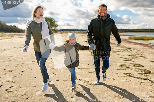 Image of happy family running along autumn beach