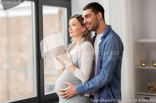 Image of man hugging pregnant woman at window at home