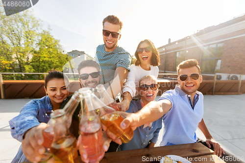 Image of happy friends toasting drinks at rooftop party