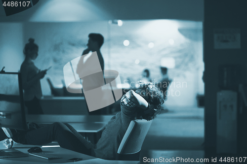 Image of businessman sitting with legs on desk at office