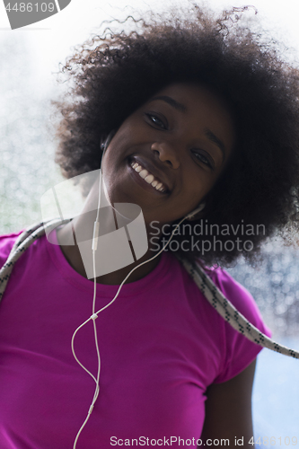 Image of portrait of young afro american woman in gym while listening mus