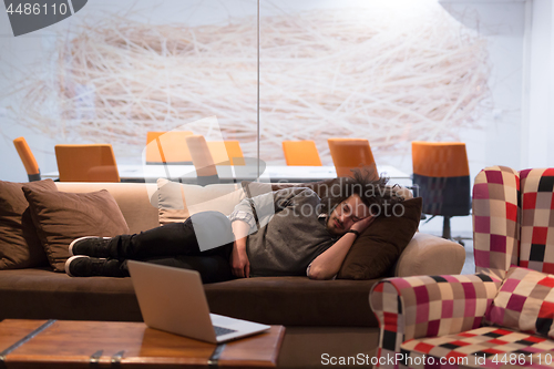 Image of man sleeping on a sofa  in a creative office