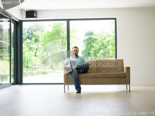 Image of man on sofa using tablet computer