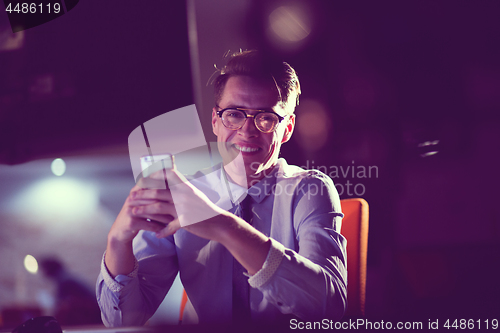 Image of man using mobile phone in dark office