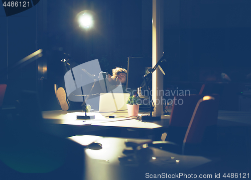Image of businessman sitting with legs on desk at office