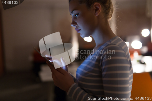 Image of woman working on digital tablet in night office