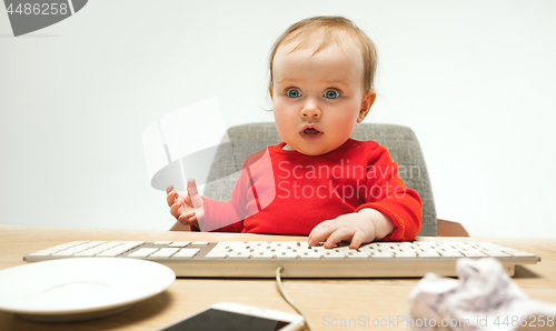 Image of Happy child baby girl toddler sitting with keyboard of computer isolated on a white background