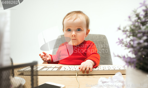 Image of Happy child baby girl toddler sitting with keyboard of computer isolated on a white background