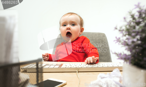 Image of Happy child baby girl toddler sitting with keyboard of computer isolated on a white background