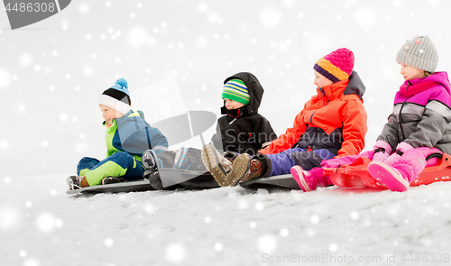 Image of happy little kids sliding on sleds in winter