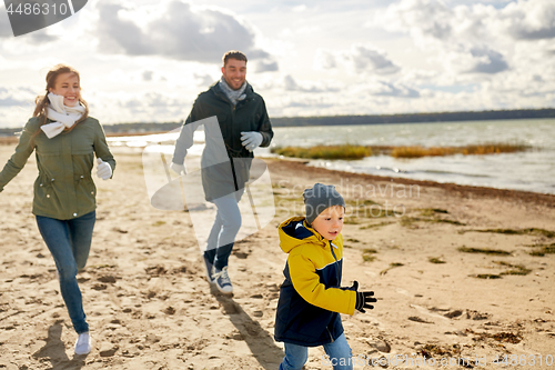 Image of happy family running along autumn beach