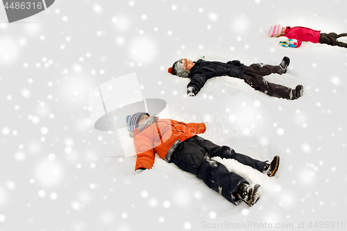 Image of happy little kids making snow angels in winter