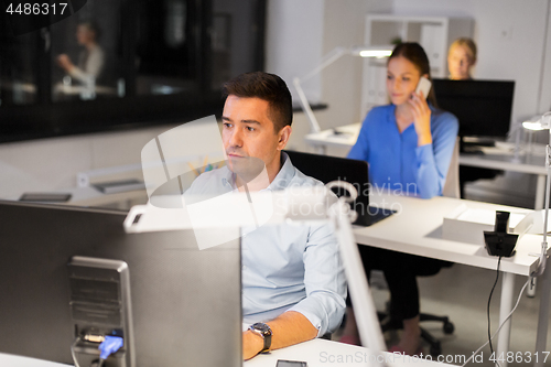 Image of man with computer working at night office