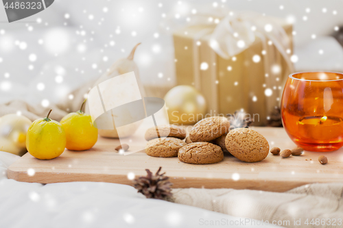 Image of cookies, lemons, candle and christmas gift at home