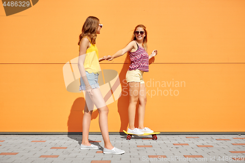 Image of teenage girls riding skateboard on city street