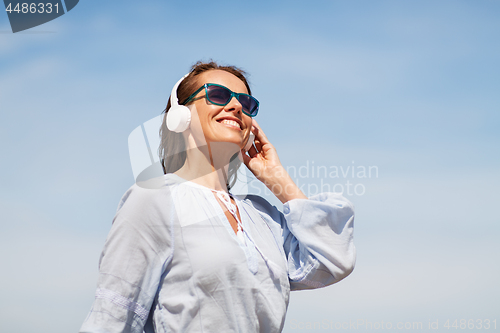 Image of woman with headphones over blue sky